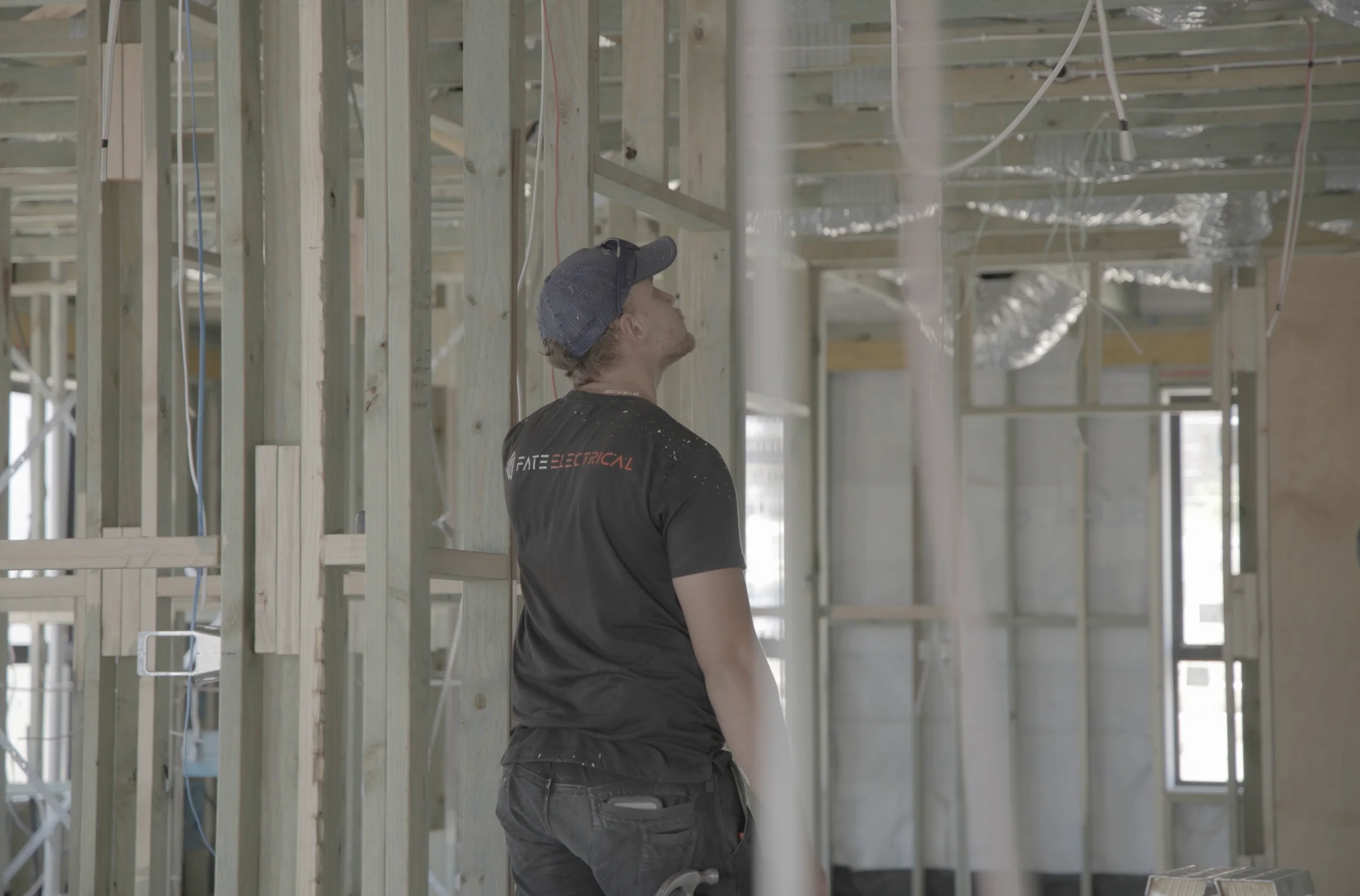 A FATE electrician in a FATE Electrical shirt at rough-in inside a timber-framed Canberra new build