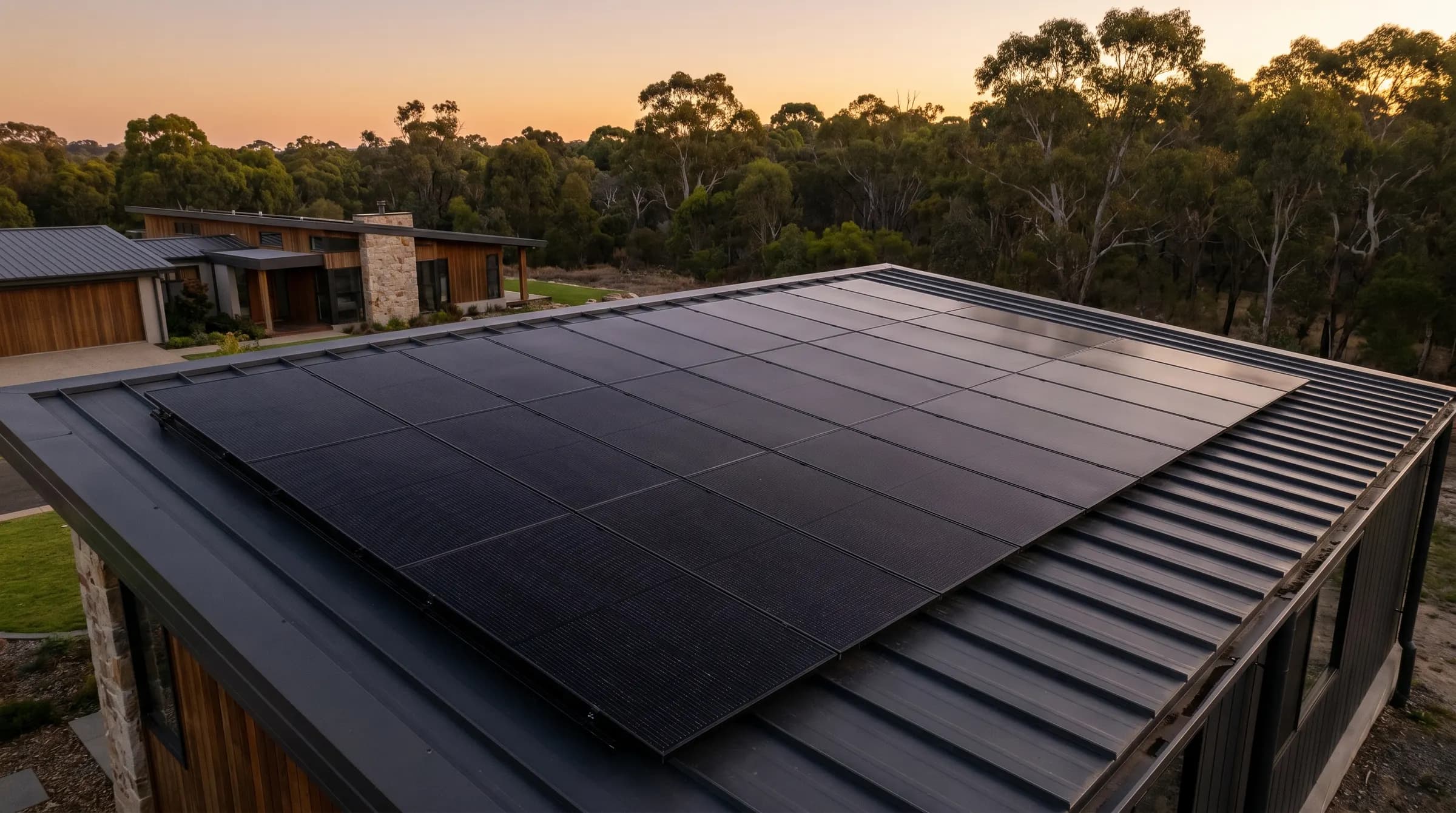 Clean all-black solar array flush on a dark roof, Canberra bushland beyond at dusk