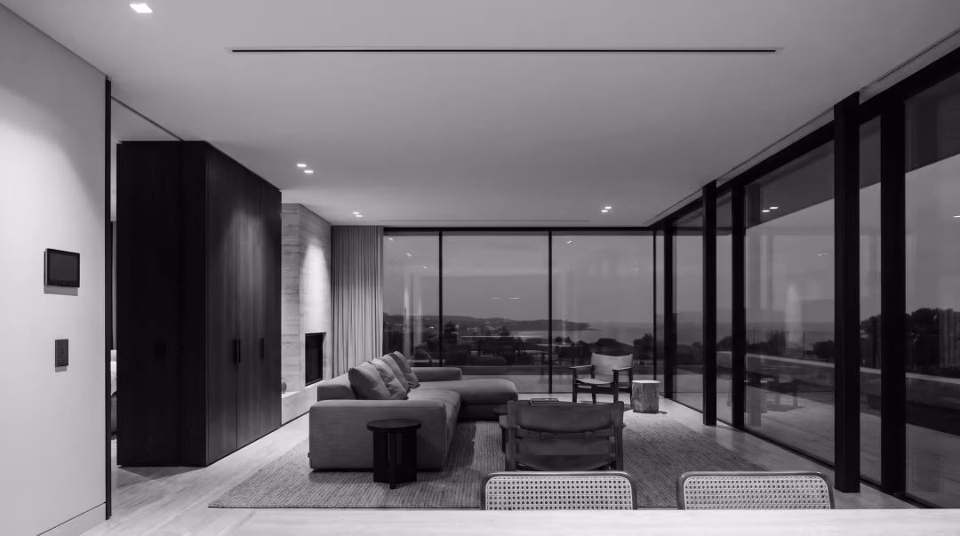 Luxury Canberra living room at dusk with concealed air conditioning — only a slim ceiling diffuser and a wall control panel show
