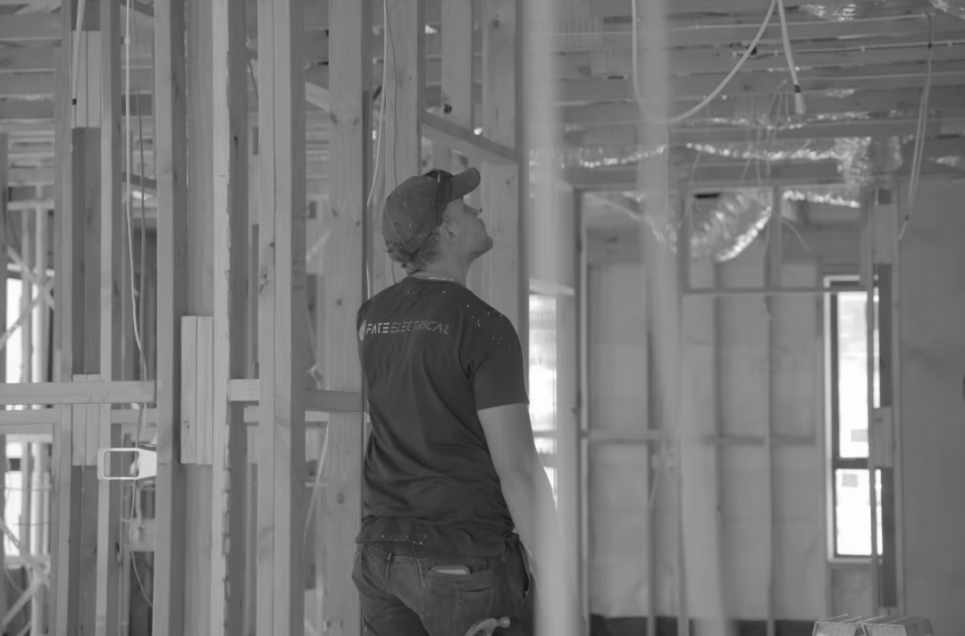A FATE electrician in a FATE Electrical shirt at rough-in inside a timber-framed Canberra new build